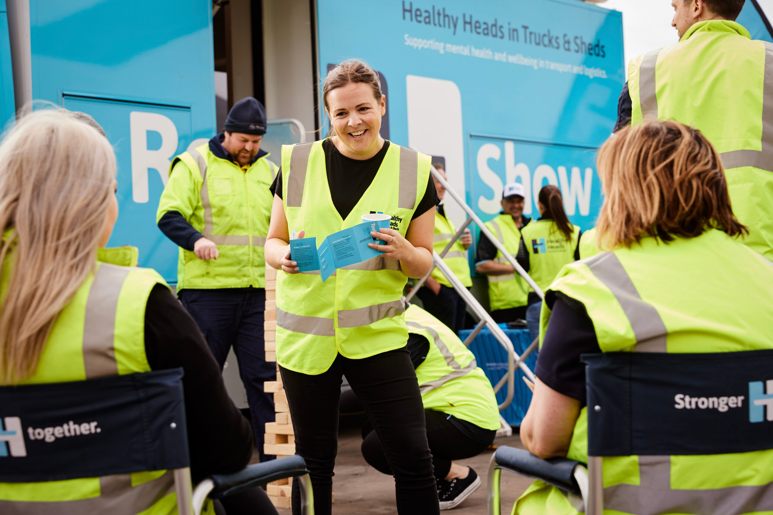 A lady with a brochure in an event and a group of colleagues around her